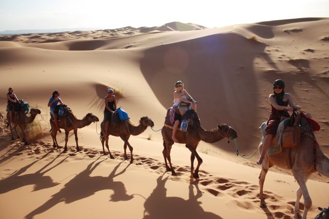 riding camels through Sahara desert dunes